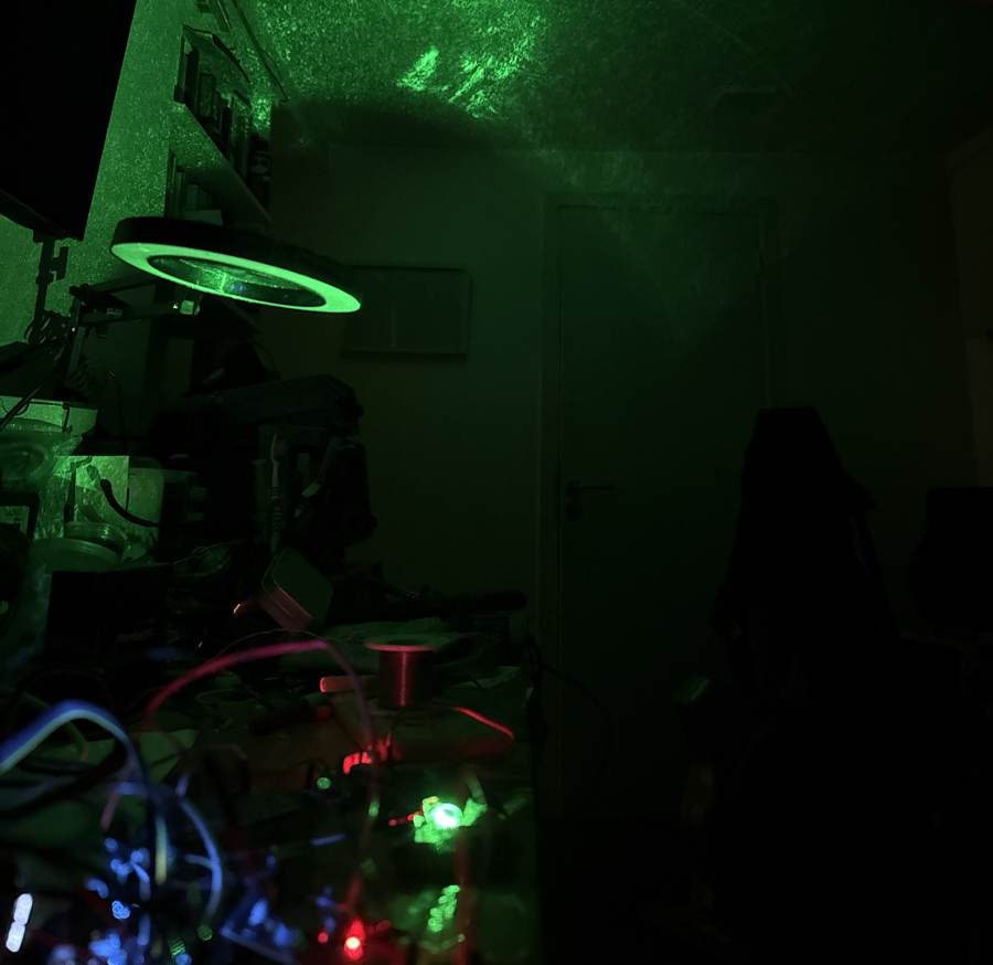 Banco de trabajo en penumbra iluminado por el láser verde de 520 nm reflejado en la pared